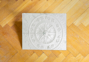 reflection of ceiling stucco in a mirror lying on a Herringbone parquet