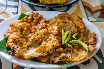 Enjoying Delicious Corn Fritters with Green Chilies on a White Plate