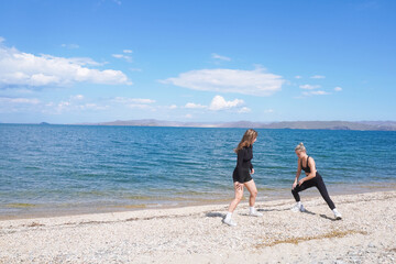 Women engaging in cardio training on a beach under blue skies during daytime