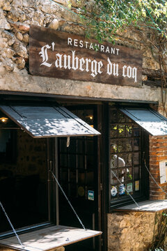 Rustic entrance of traditional restaurant L auberge du coq with wooden sign and stone walls in the medieval village of Perouges France August 19 2025