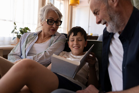 Grandparents and grandson reading together on a cozy sofa at home