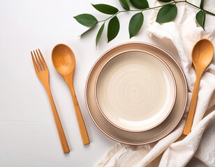 A natural, pastel background with plates, wooden cutlery, a linen cloth, and a green sprig. Table setting, tableware