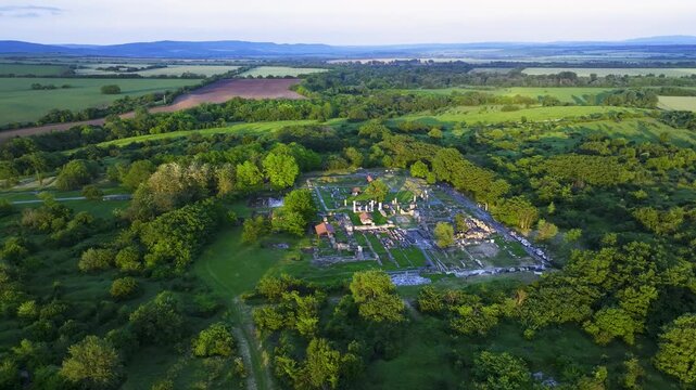 Orbiting drone view of Nicopolis ad Istrum at golden hour, with sunlight casting over ancient Roman