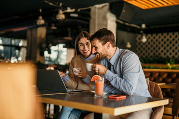 Business people working on laptop and drinking coffee in cafe