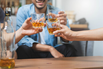 Group of friends toasting glasses whisky in the party.