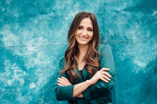 Happy businesswoman standing with arms crossed in front of tie dye backdrop