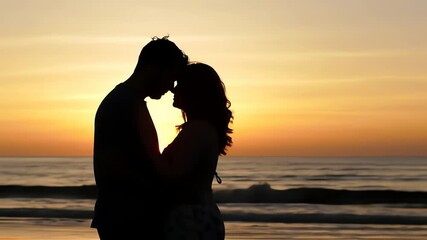 Silhouette of a romantic couple in love embracing on the beach with a beautiful golden sunset over the ocean