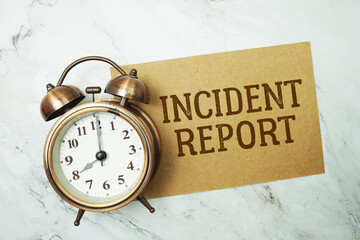 Incident Report text written on paper card with alarm clock on marble background