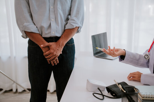 A man is consulting a doctor about hemorrhoids. Squeezing his buttocks. Sees a proctologist to discuss anal problems. Hemorrhoids or treatment concept