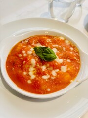Traditional Italian dish of Gnocchi alla Sorrentina served on a white plate. Soft potato gnocchi baked in a rich tomato sauce with melted mozzarella and fresh basil.