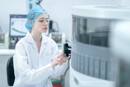 A medical technologist loads a sample rack into an automated immunoassay analyzer, initiating the biomarker testing process for diagnostics in a certified laboratory.