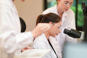 Obraz premium A team of medical researchers discusses their experiment's results. They are analyzing data and microscope findings together in a clinical laboratory to reach a conclusion.