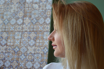 Young Caucasian blonde woman in white sweater looking away. Portrait of modern woman.