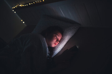 Girl using smart phone while lying on bed in bedroom