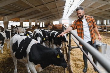 Farmer holding bucket taking care of cows in barn © Serhii