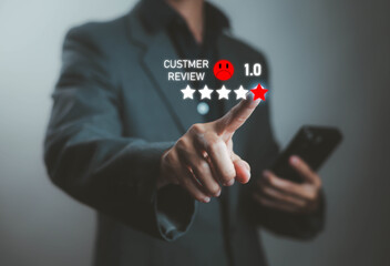 Businessman pressing one-star customer review rating with sad face icon on virtual screen, concept of negative feedback, poor service, dissatisfaction, complaint, and online reputation management.