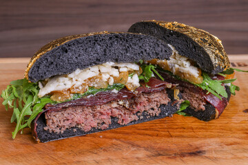 Panino da pub nero ripieno di hamburger di carne, pecorino, rucola, bresaola e cipolle caramellate...