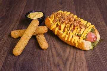 Panino da hot dog ripieno di hot dog artigianale e guarnito con salsa ai friarielli, senape e bacon croccante, servito in un pub con contorno di mozzarella filante fritta