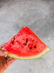 A person holding a slice of watermelon in their hand