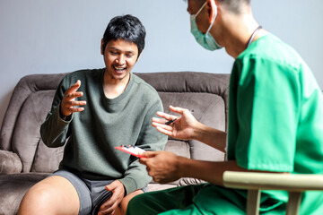 Male Patient Happily Discusses His Health With a Doctor During a Home Visit