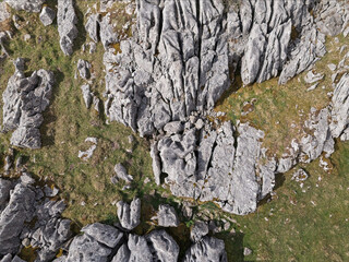Dramatic aerial view of rugged rock formations of Limestone pavement and patches of vibrant green grass.