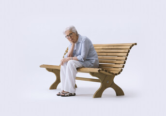 Elderly Woman Alone and Sad Sitting on a Bench, Holding Her Head in Her Hands. Concept of...