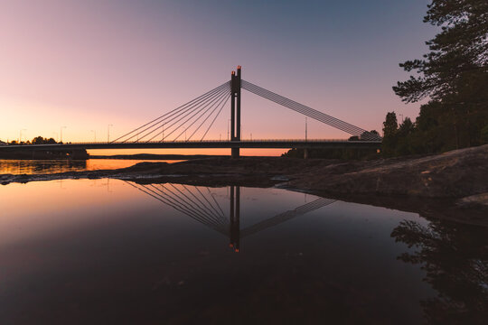 Lumberjack&rsquo;s Candle Bridge in Rovaniemi Finland reflecting on Kemijoki River at sunset
