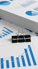 Black binder clip on financial charts showing data driven growth business growth analytics