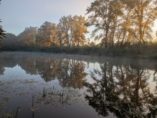 Early autumn morning with fog on the field and on the river