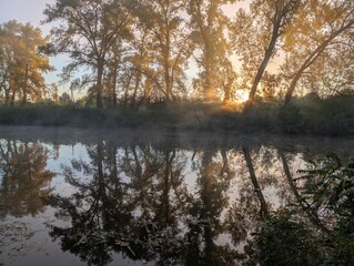 Obraz premium Early autumn morning with fog on the field and on the river