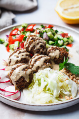 Falafel - chickpea balls on plate with tahini, vegetable salad and coleslaw.