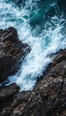 Waves crash against jagged rocks with foamy splashes and raw force
