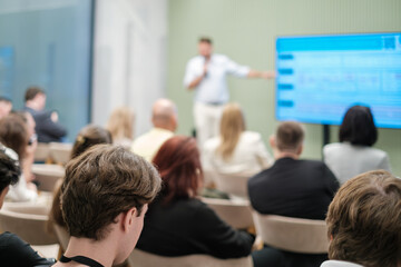 Group of people attending a presentation where speaker explains concepts using visual aids