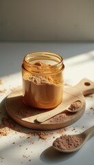 Glass jar filled with light brown powder and spoons on wooden board