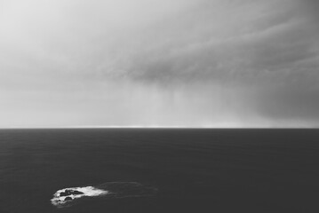 Minimalist black and white seascape with rocky islet