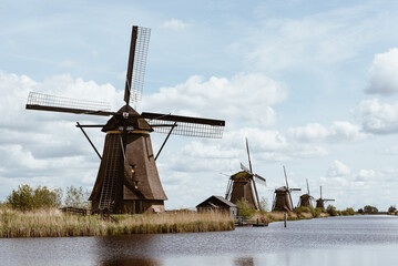 Row of historic Dutch windmills along a canal with tall grass