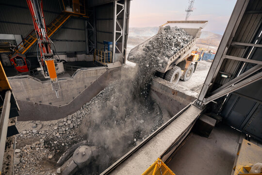 Big mining truck unloads ore for crusher, processing plant. Stones is crushed to recover copper, gold, iron metal