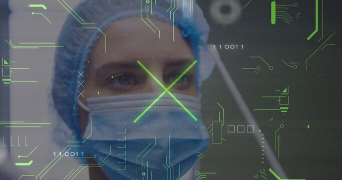 Mid adult female medic scanning circuit overlay with binary digits in operating room, with cap mask