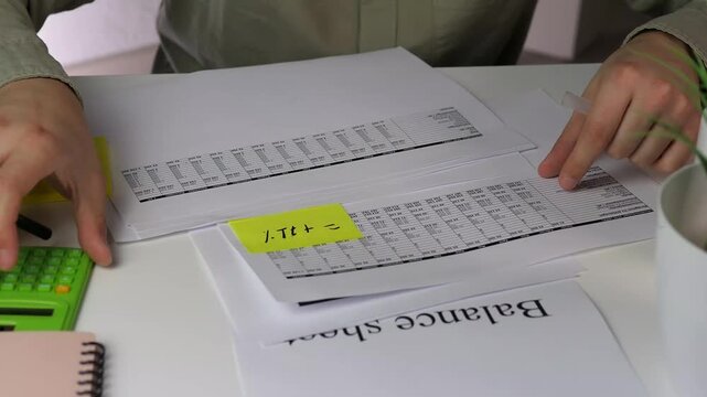 A professionals hands double-check highlighted figures on accounting documents with a calculator. Ideal for suspenseful audits, meticulous reporting, or error-resolution stories.