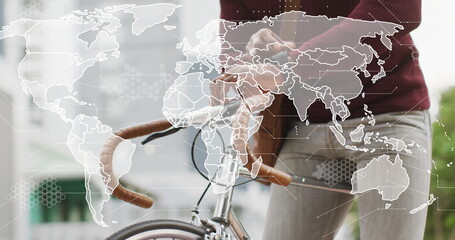 Gripping drop handlebars Black man wearing burgundy sweater standing on sidewalk, world map overlay