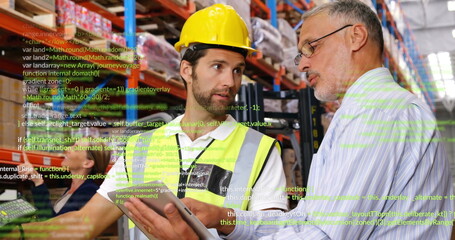 Worker wearing hard hat discussing inventory on tablet with boss in warehouse, amid shelving racks