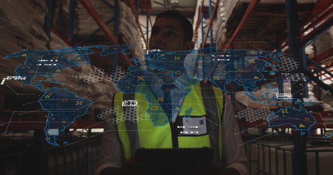 Using tablet hi-vis vest clad worker viewing digital map overlay in warehouse aisle, racks, pallets