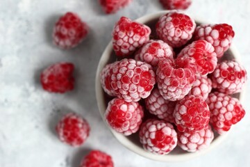 Top View of Icy Raspberries. Chilled Bowl of Frozen Berries for Dessert on Light Textured Background