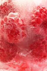 Obraz premium Frozen Raspberry in Ice, close up. Refreshing and Vibrant Background for Healthy Summer Food.