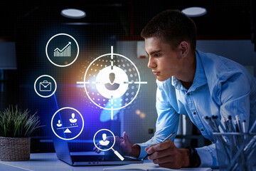 Young professional analyzing data on laptop with digital icons in modern office environment