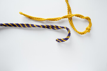 Yellow and purple ropes lying on a white background representing Spanish Holy Week