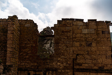 A stone building with a window and a mountain in the background