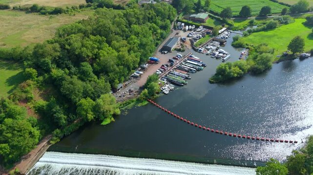 Flying drone over Gunthorpe Weir and River Trent in Nottinghamshire England with navigation canal, rural farmland and glowing summer sunset horizon