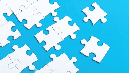 Fototapeta premium A collection of white puzzle pieces are scattered on a bright blue background, some connected, others floating apart, suggesting incomplete or missing solutions