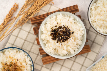 A bowl of white rice topped with seasoned seaweed and white sesame.